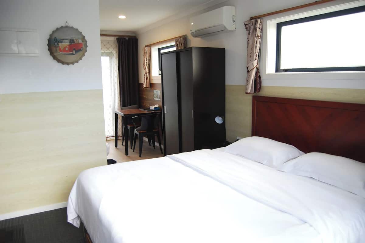 A hotel room with a bed, a desk, and a wardrobe.