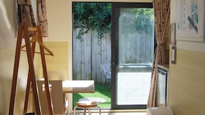 Una habitación con una puerta corrediza de vidrio que da a un patio, una mesita, una silla y un caballete de madera.