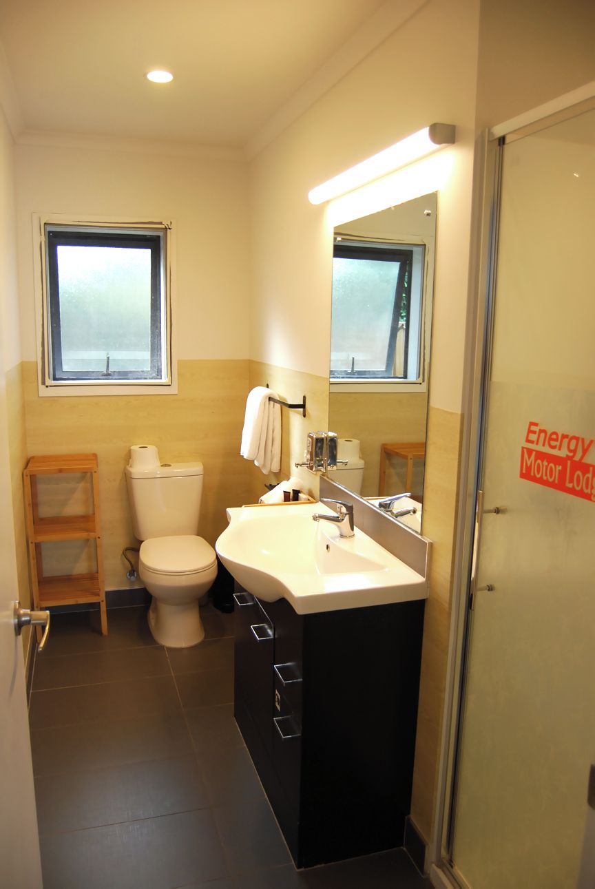 A compact bathroom with a toilet, sink, and mirror.