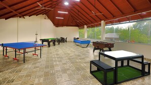 A spacious indoor recreational area with a ping pong table, foosball table, and pool table.