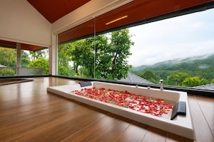 Una habitación amplia con un gran ventanal que da a un paisaje exuberante.