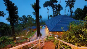 A staircase leading to a building with a blue roof, surrounded by trees and greenery.