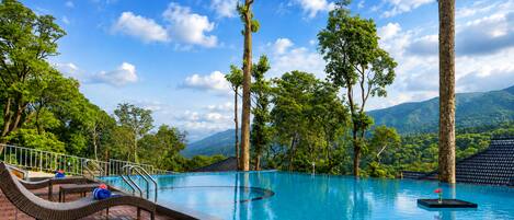 Zona de piscina con sillones de descanso y vistas a un paisaje montañoso.
