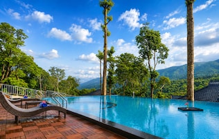 Zona de piscina con sillones de descanso y vistas a un paisaje montañoso.