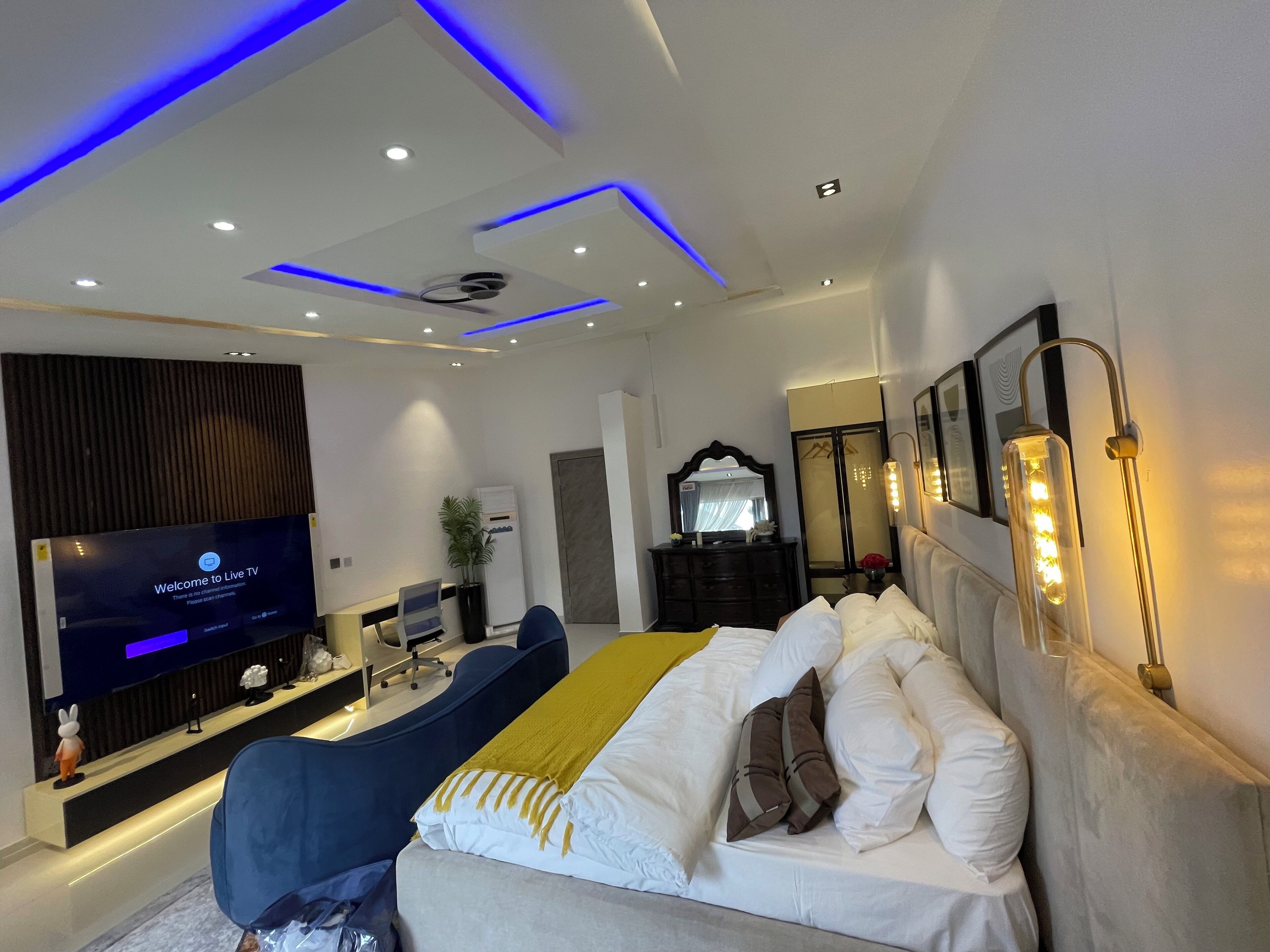 A modern hotel room with a bed, a TV, a desk, and a mirror.