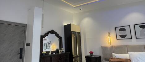 A modern bedroom with a bed, dresser, mirror, and artwork on the walls.