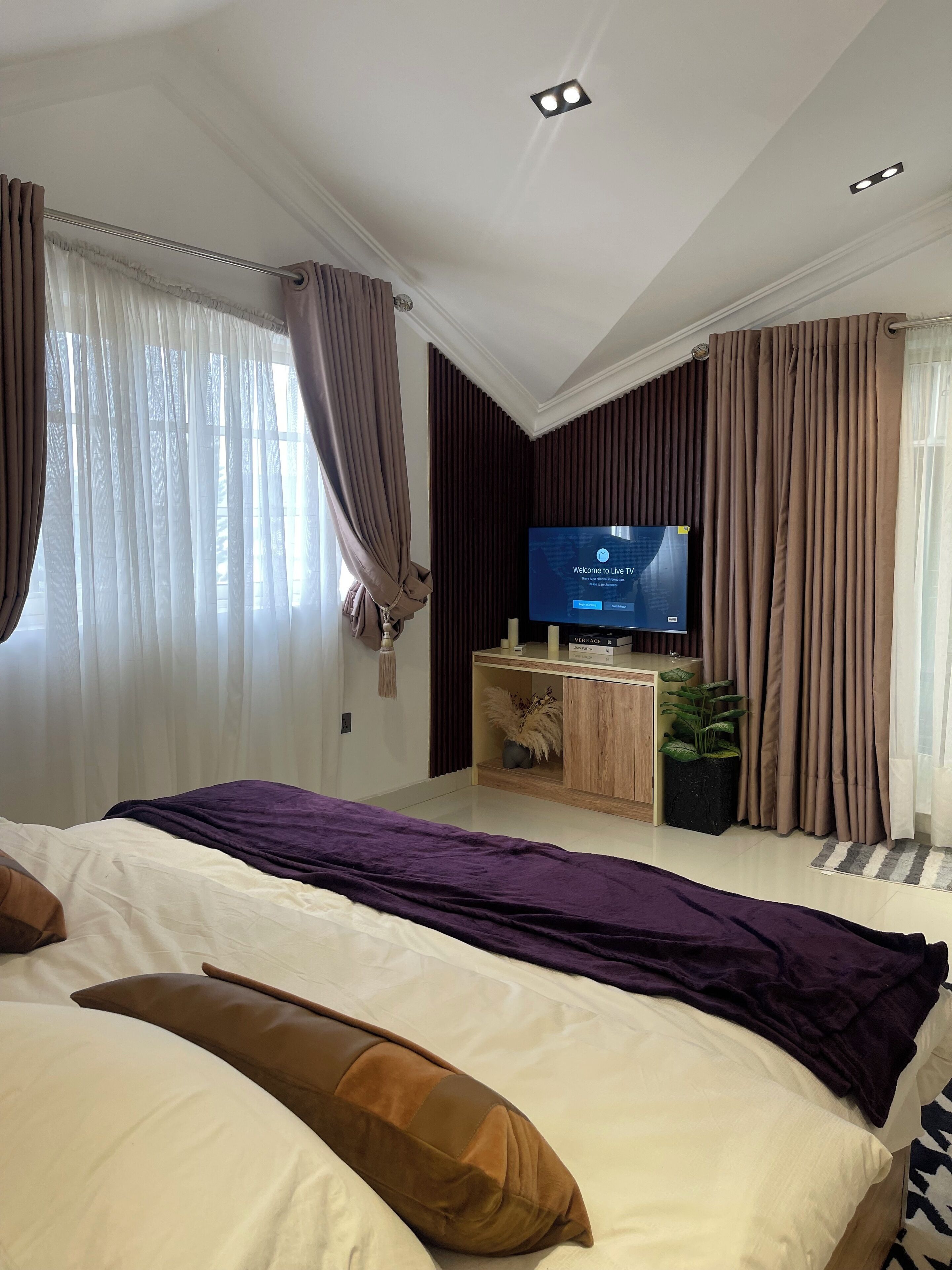 Ein modernes Hotelzimmer mit einem großen Bett, einem Flachbildfernseher und einem Holzkonsolentisch mit Dekoration.