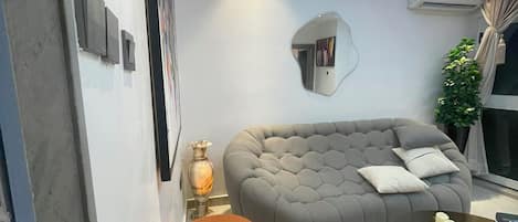 Un salon moderne avec un canapé gris, un banc en bois et une table basse en verre.