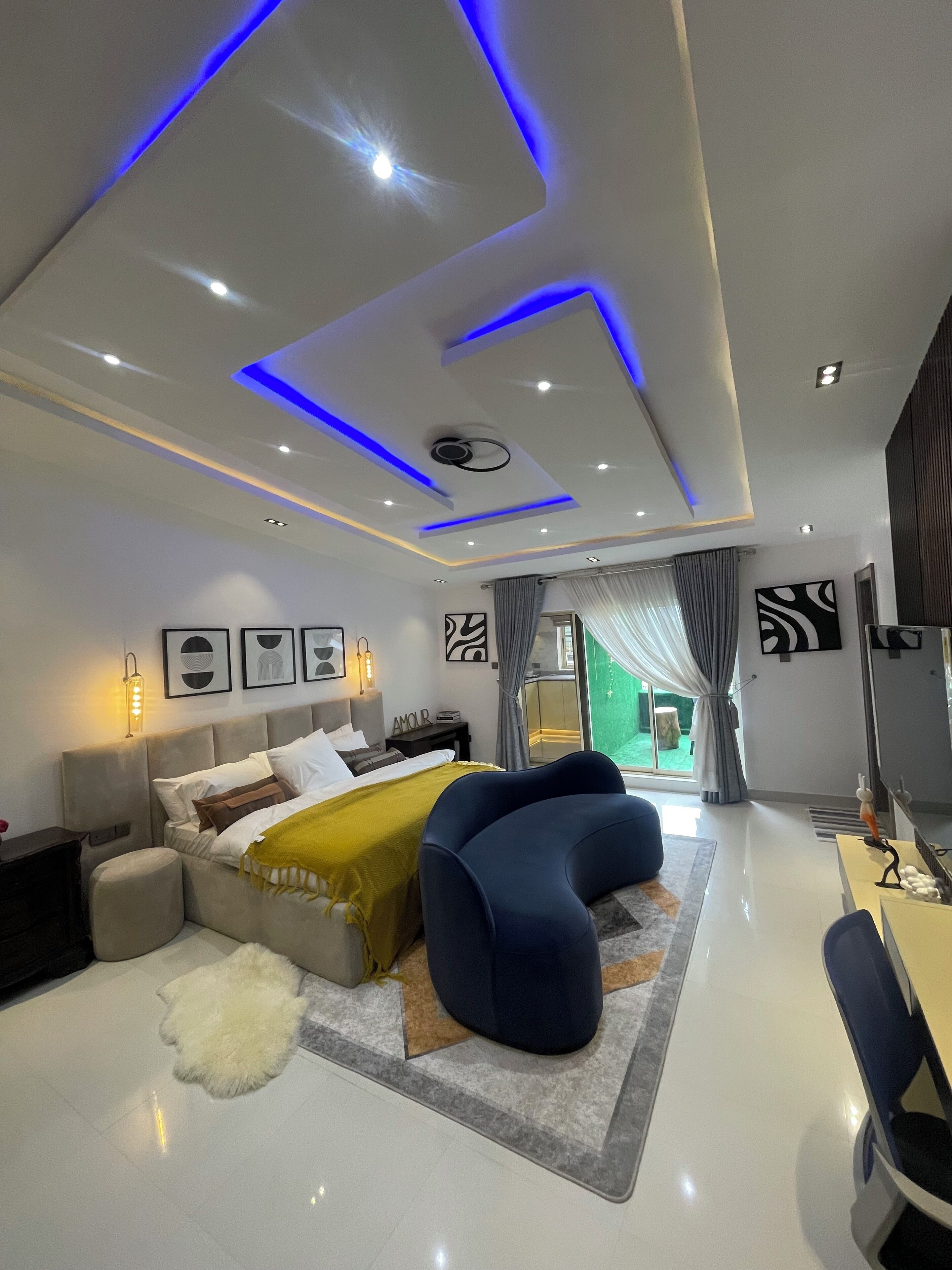 A modern bedroom with a bed, a desk, and a view of the outdoors.