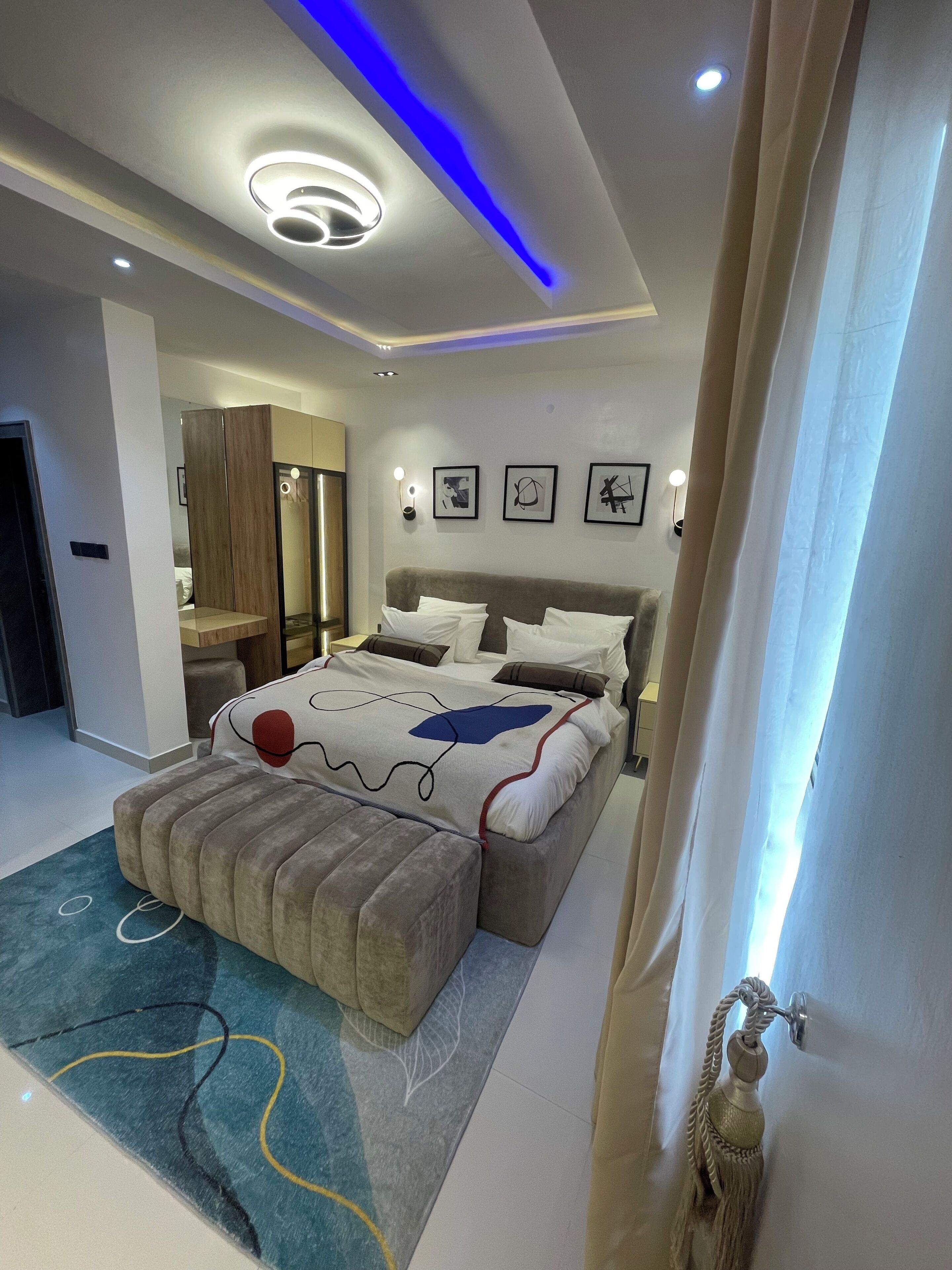 Een moderne slaapkamer met een groot bed, een kaptafel en een plafond met blauwe LED-verlichting.