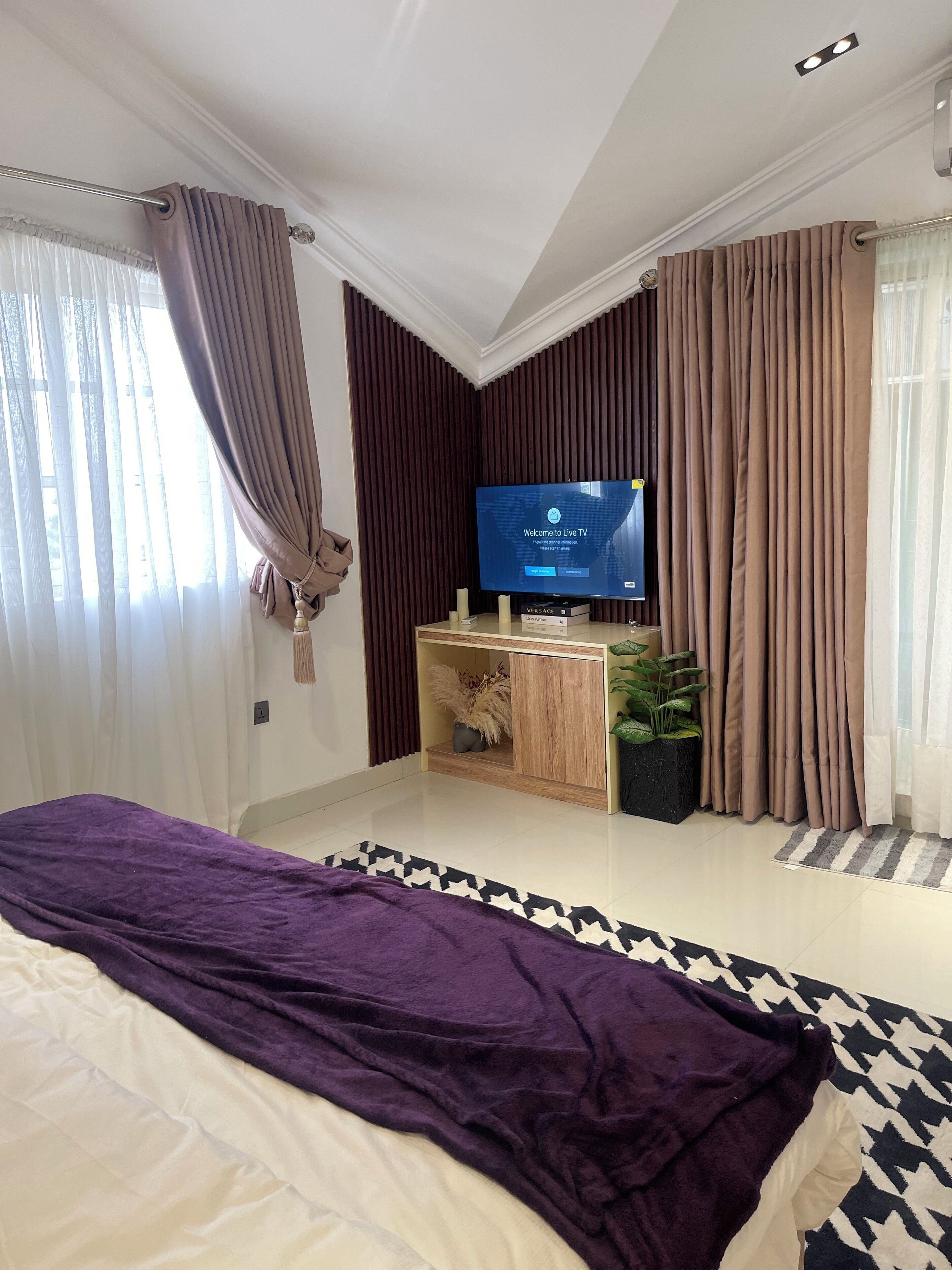 A modern bedroom with a large bed, a TV, and a console table with decorative items.