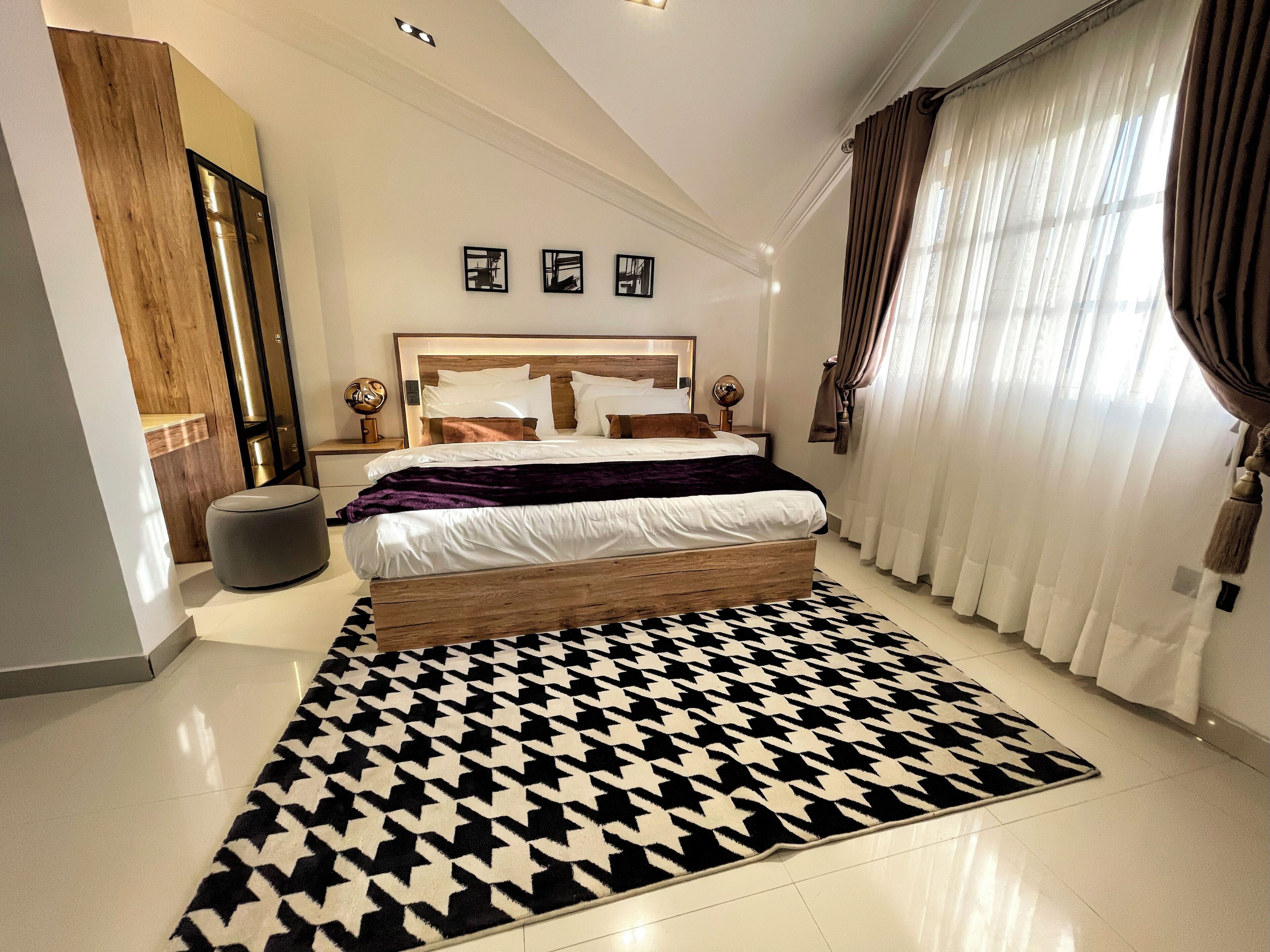Une chambre à coucher moderne avec un grand lit, un tapis à motifs et une armoire en bois.