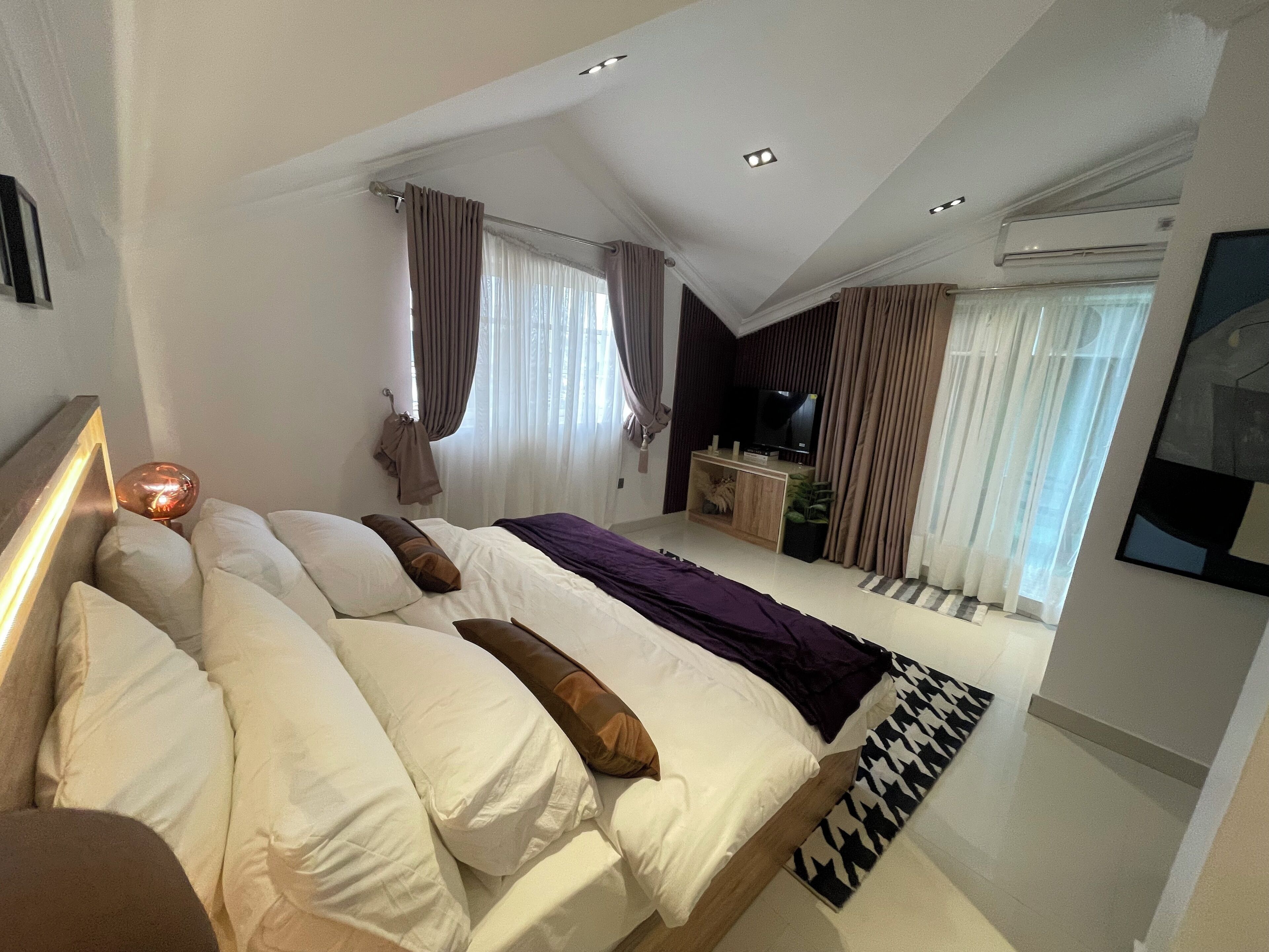 Un dormitorio moderno con una cama grande, un televisor y una pequeña zona de escritorio.