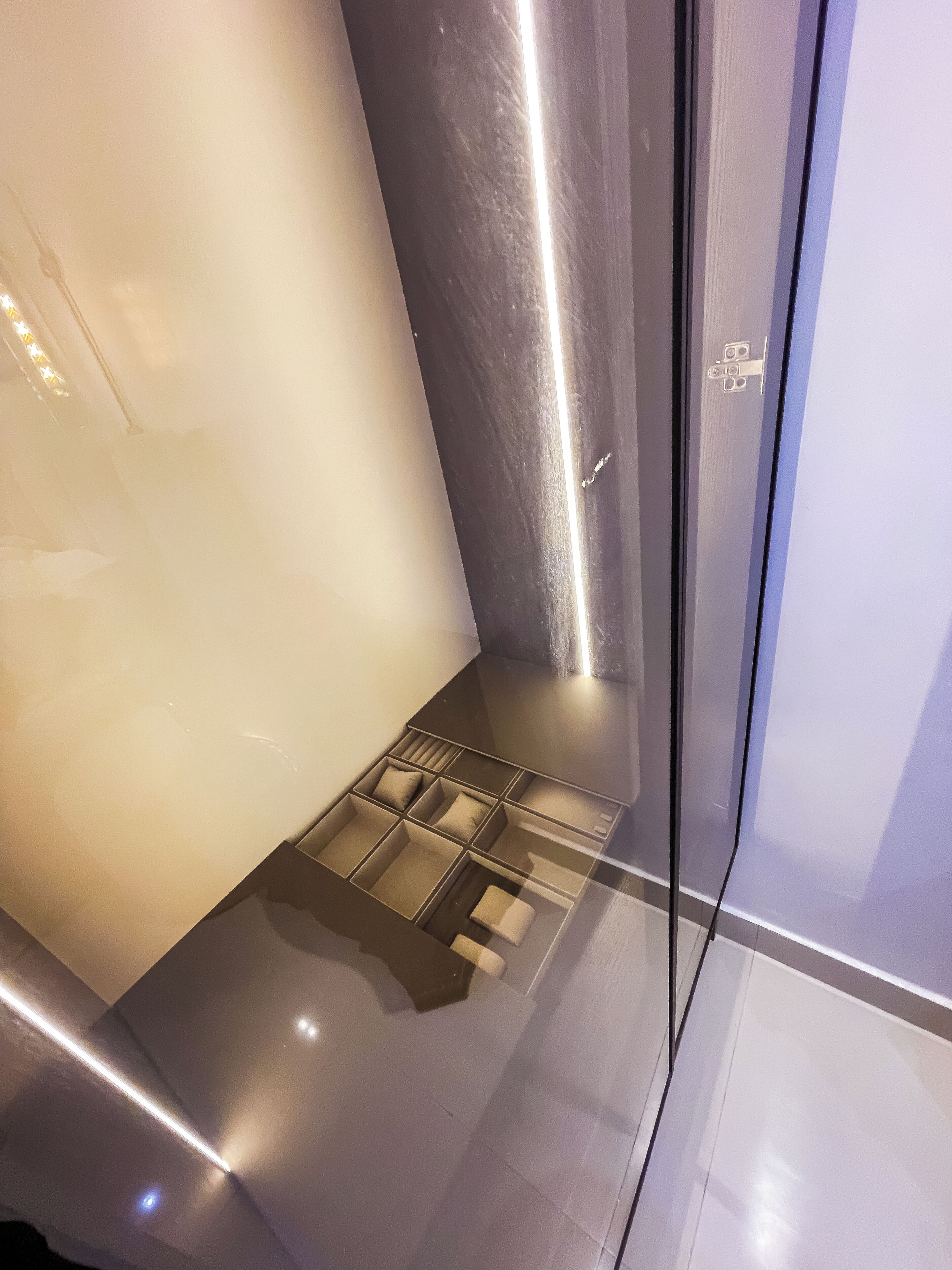 Un baño moderno con cabina de ducha de vidrio, toallero integrado y desagüe visible.