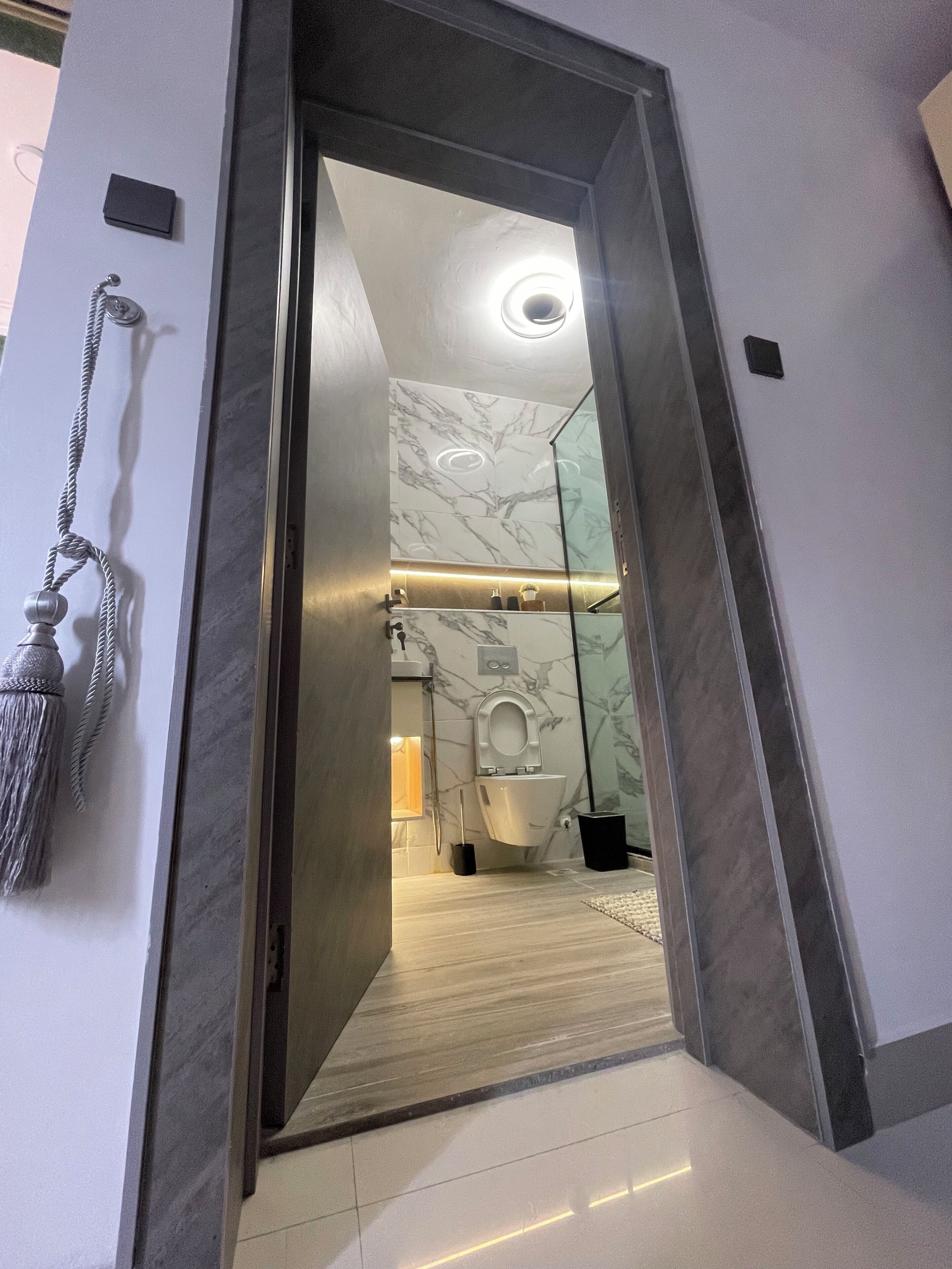 Un baño moderno con piso de mármol, inodoro y cabina de ducha de vidrio.