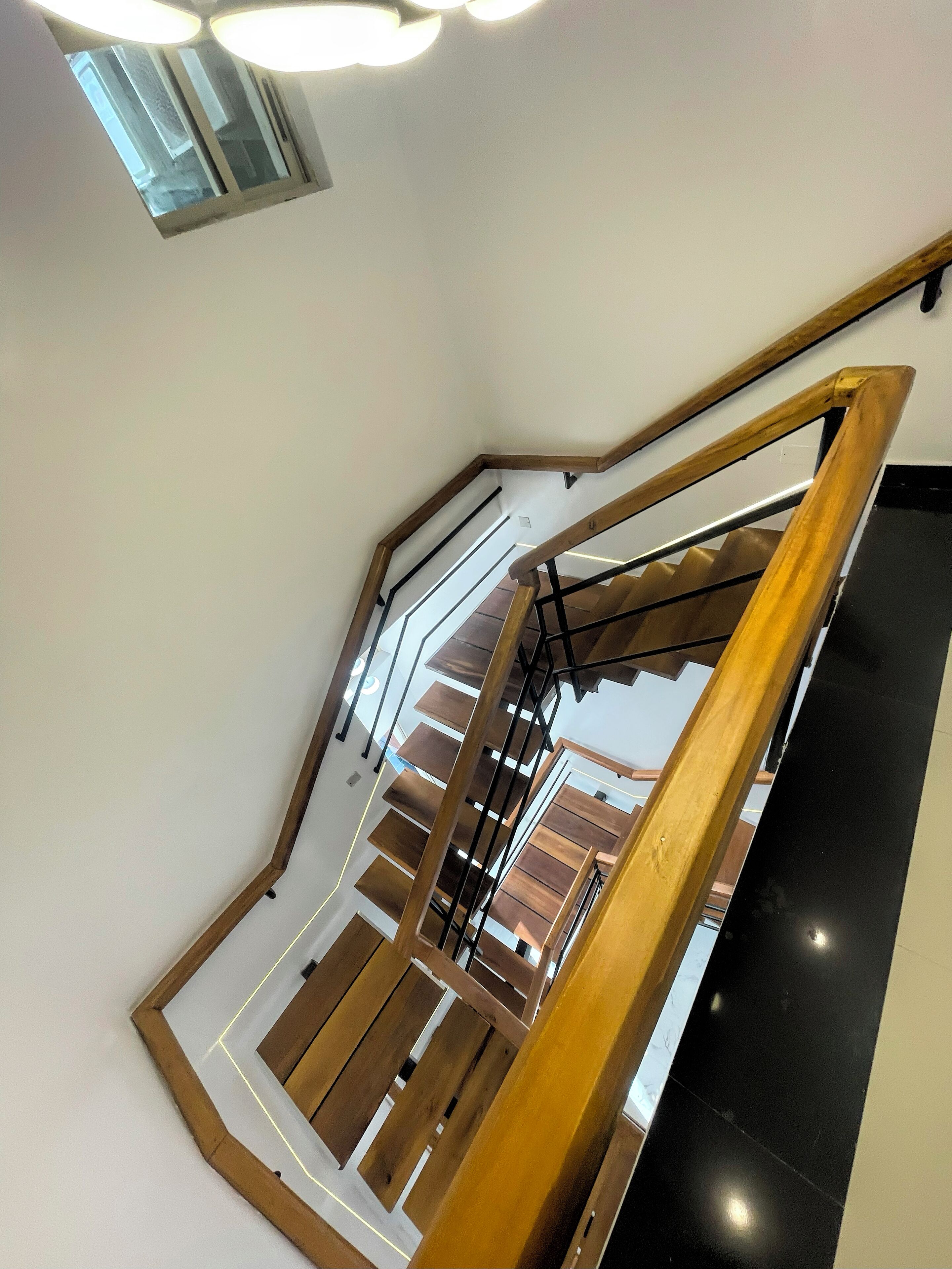 A modern staircase with wooden railings and a black wall.