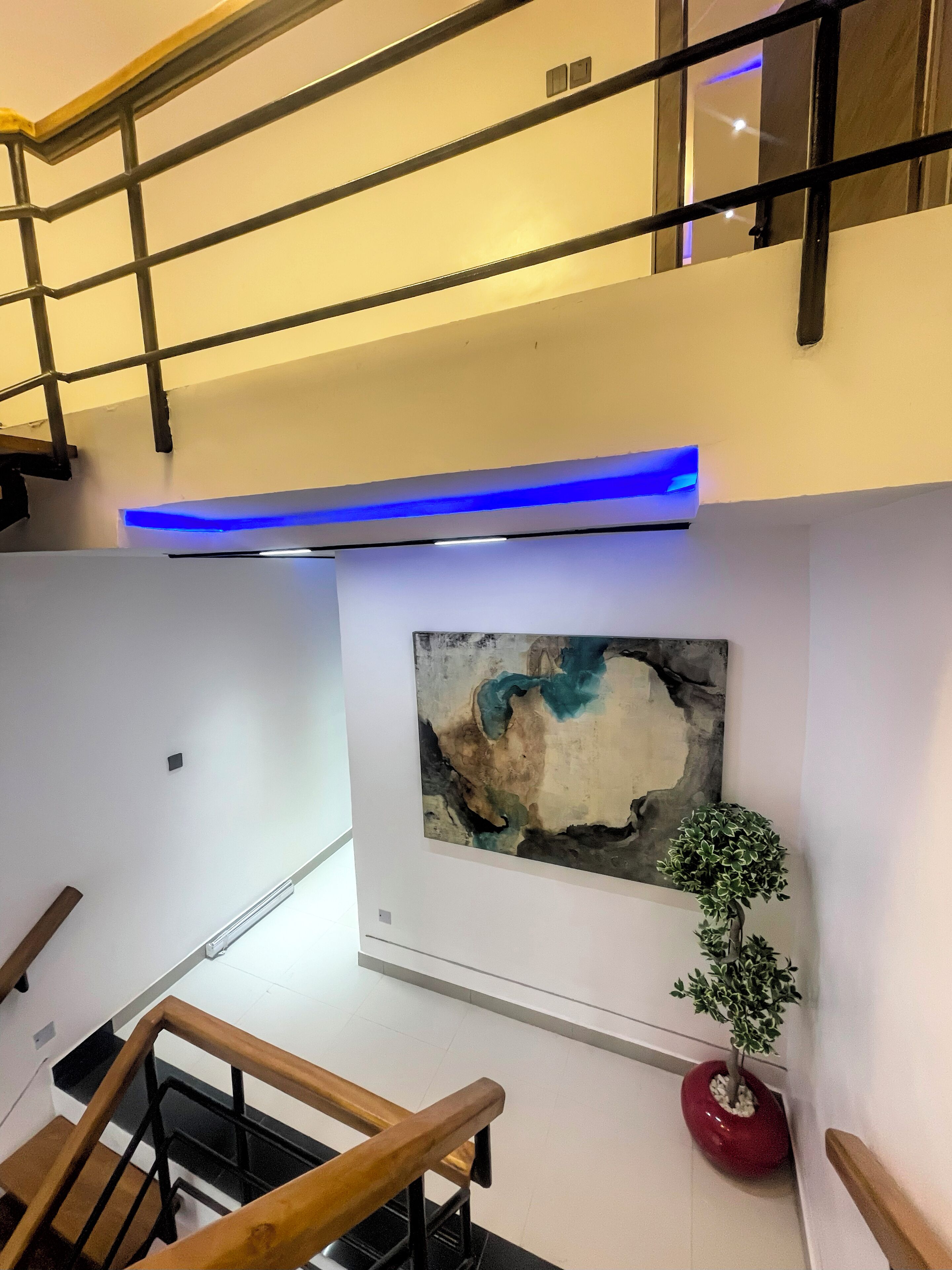 Ein modernes Interieur mit einer Treppe, einem an der Wand befestigten abstrakten Gemälde und einem Blumentopf.