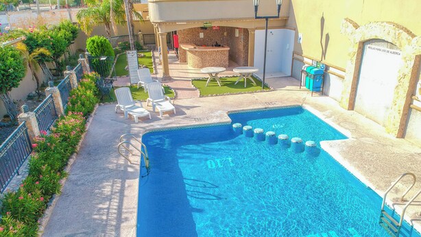 A swimming pool with lounge chairs and a bar area. - Hotel San Martin (Hermosillo)