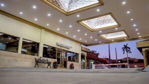 A hotel reception with a clear view of the entrance, a bench, and potted plants. - Hotel San Martin (Hermosillo)