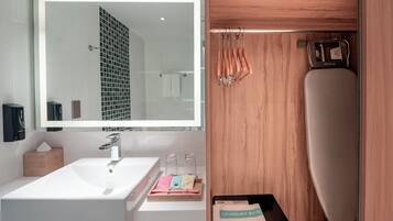 A modern bathroom with a large mirror, a white sink, and a wooden vanity.