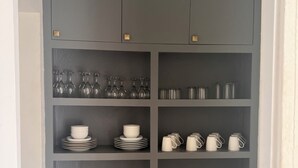 A grey storage unit with multiple shelves containing kitchenware.