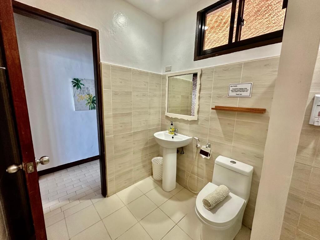 Un baño con lavamanos, inodoro y espejo.
