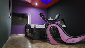 A modern room with a bed, a unique curved chair, and a purple wall.
