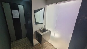A modern bathroom with a sink, mirror, and a door leading to another room.
