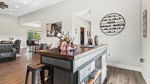 Un vaste espace de vie agrémenté d’une table basse en bois, de fauteuils en cuir et d’une cuisine moderne en arrière-plan.