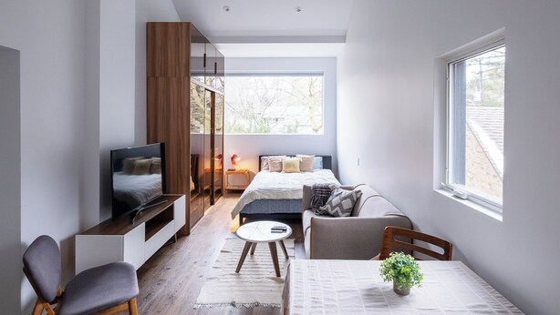 A modern, compact living space with a bed, seating area, and a TV. - Queen size loft in nature right in the city (Toronto)