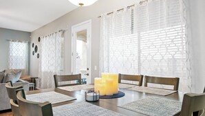 A dining area with a wooden table, six chairs, and a candle centerpiece. - Tucson pool home -  pets, putting green, no hidden fees (Tucson)