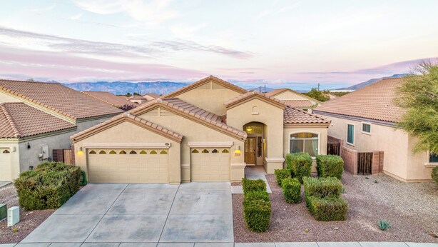 A residential area with multiple houses featuring similar architectural styles, including beige stucco walls and terracotta roofs. - Tucson pool home -  pets, putting green, no hidden fees (Tucson)