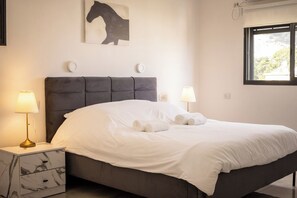 Ein Schlafzimmer mit einem Bett, zwei Nachttischlampen, einem Marmornachtisch und einem Wandbild.