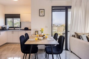 A dining area with a table set for six, a sofa, and a view of the outdoors.
