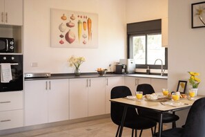 Eine moderne Küche mit weißen Schränken, einer schwarzen Arbeitsplatte und einem für das Frühstück gedeckten Esstisch.