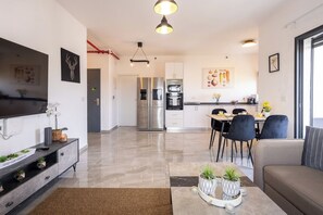 Eine moderne Küche mit Edelstahlgeräten, ein Essbereich mit Tisch und Stühlen sowie ein Wohnzimmer mit Sofa und Couchtisch.