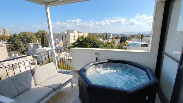 Un balcón con un jacuzzi, un sofá y vistas a la ciudad.