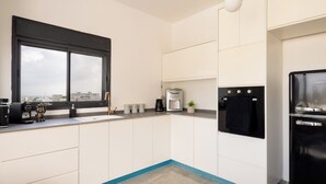 Una cocina moderna con un gran ventanal, un refrigerador negro y una cafetera.