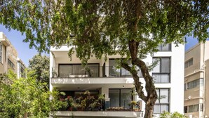 A multi-story residential building with balconies, surrounded by greenery and parked cars. - Mamad Stylish Green Oasis | Tel Aviv Old North (Tel Aviv)