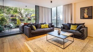 A modern living room with two dark sofas, a coffee table, and a large window with curtains. - Mamad Tel Aviv Paradise Haven (Tel Aviv)