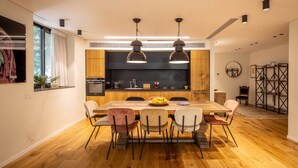 A modern kitchen with a wooden countertop, a built-in oven, and a dining area with a wooden table and chairs. - Mamad Stylish Green Oasis | Tel Aviv Old North (Tel Aviv)