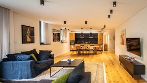 A modern living room with a sofa, coffee table, and a dining area with chairs and a table. - Mamad Tel Aviv Paradise Haven (Tel Aviv)