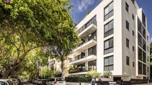A modern multi-story building with balconies, parked cars, and lush greenery. - Mamad Tel Aviv Paradise Haven (Tel Aviv)