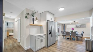 Une cuisine moderne dotée d’un réfrigérateur encastré, de meubles blancs et d’un coin repas avec une table et des chaises.