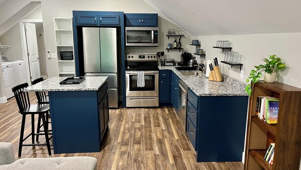 Een moderne keuken met blauwe kastjes, roestvrijstalen apparatuur en een centraal kookeiland.