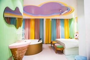 A colorful room with a round bathtub, a bed with colorful pillows, and a large mirror on the wall. - Orsom Stay Delhi (New Delhi)