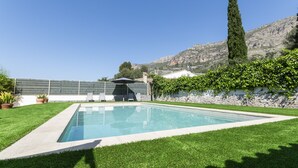 Una piscina rectangular con un borde de baldosas, rodeada de césped cuidado.