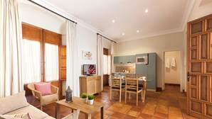 Amplia sala de estar con sofá, mesa de comedor y zona de cocina al fondo.