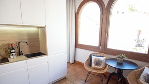 A kitchen with white cabinets, a black sink, and a window with curtains. - El Alminar en Apartamentos La Casa del Aceite (Cordoba)