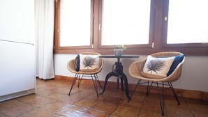 A room with two wicker chairs, a small table with a plant, and a window with curtains. - El Alminar en Apartamentos La Casa del Aceite (Cordoba)